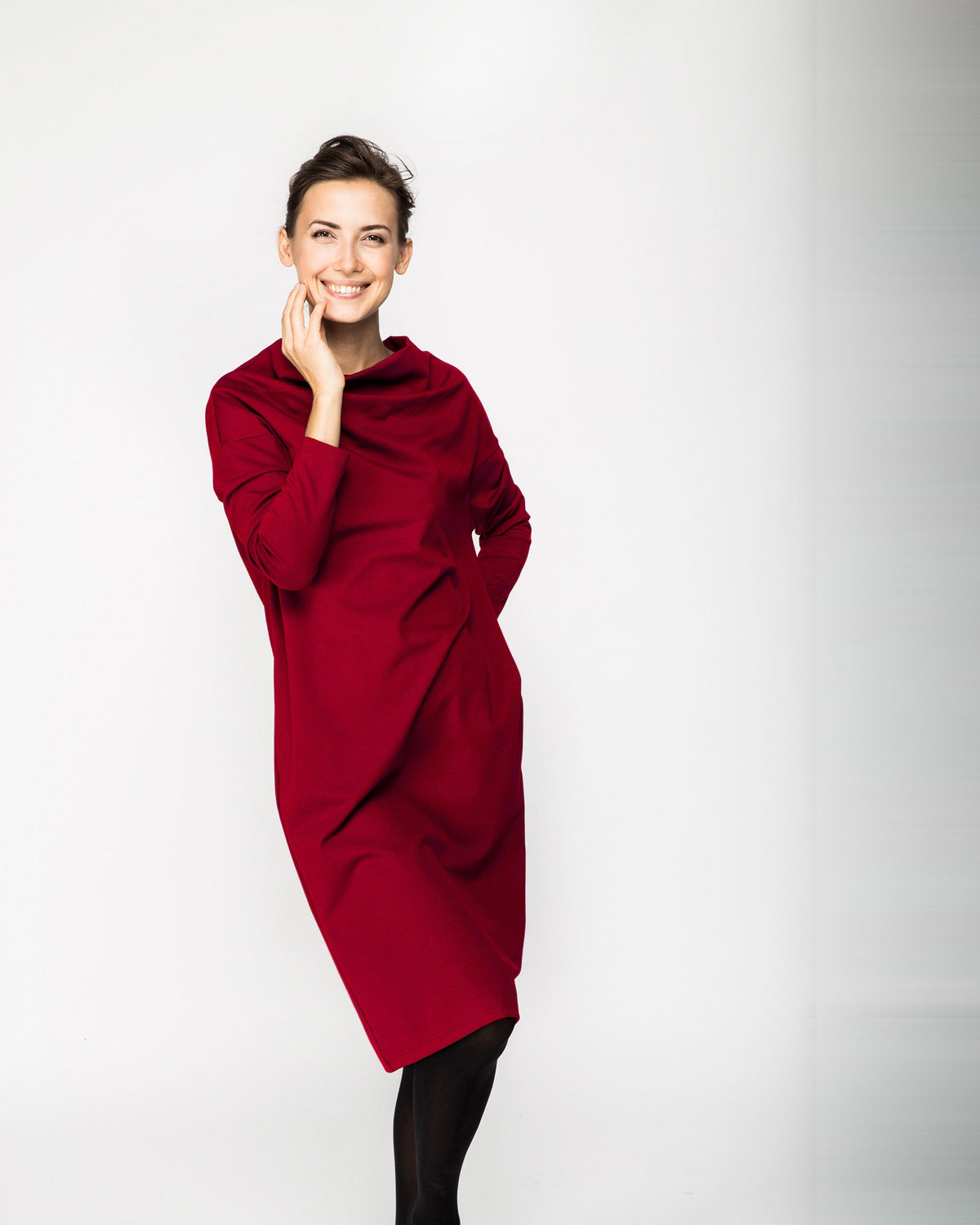 A woman wearing a dark red long-sleeve cowl-neck midi dress with side pockets, standing against a white background, front view. #Color_Red