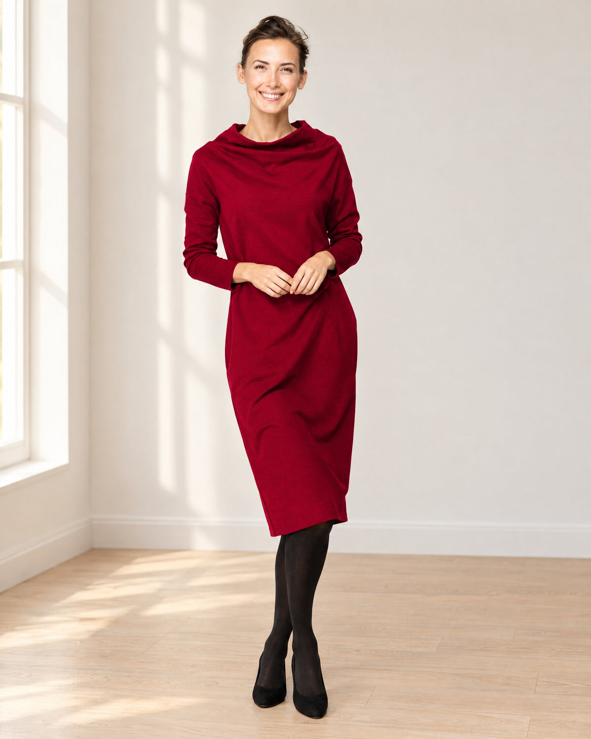 A woman wearing a dark red long-sleeve cowl-neck midi dress with side pockets, lifestyle setting. #Color_Red