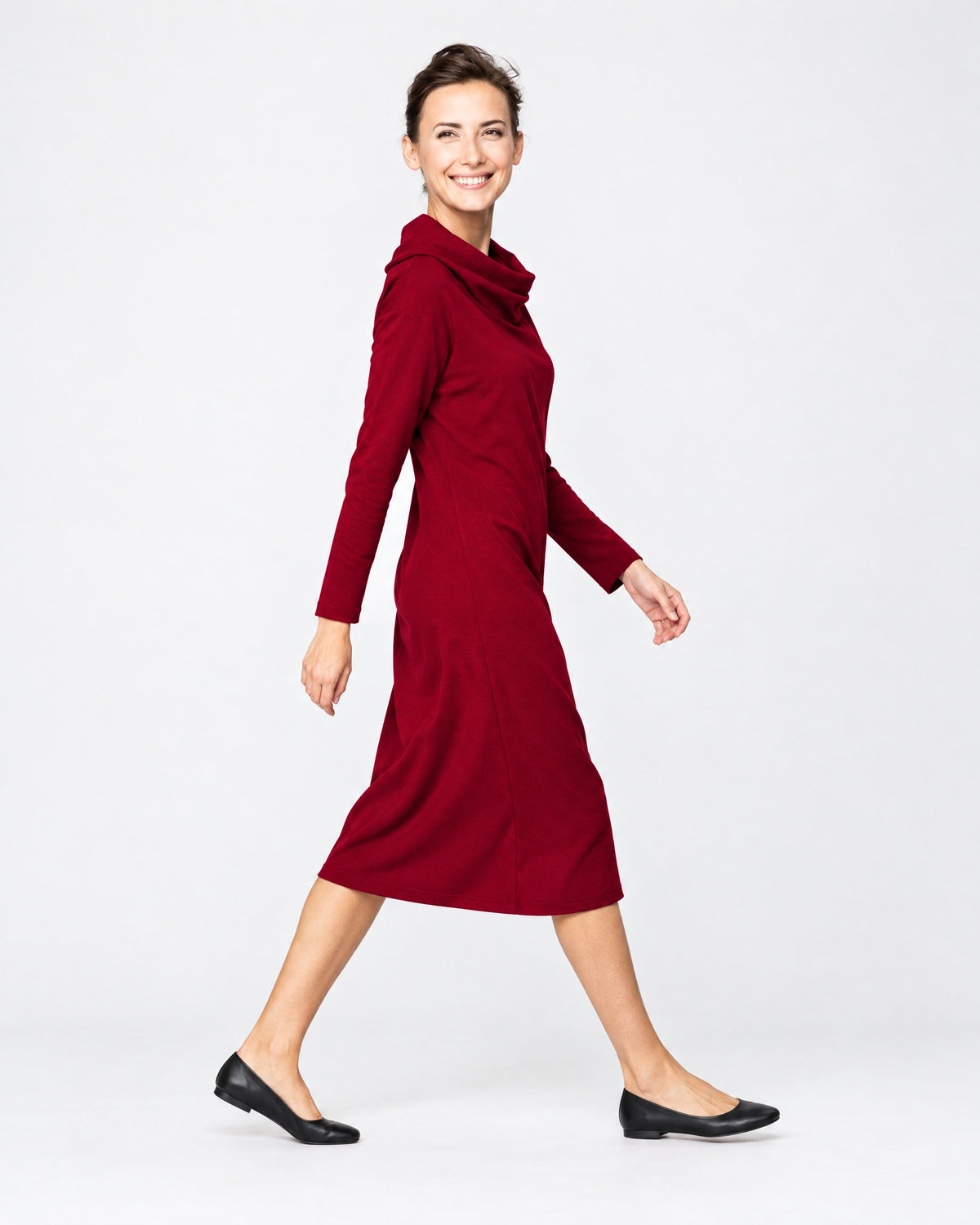 A woman wearing a dark red long-sleeve cowl-neck midi dress with side pockets, side profile in motion, studio background. #Color_Red